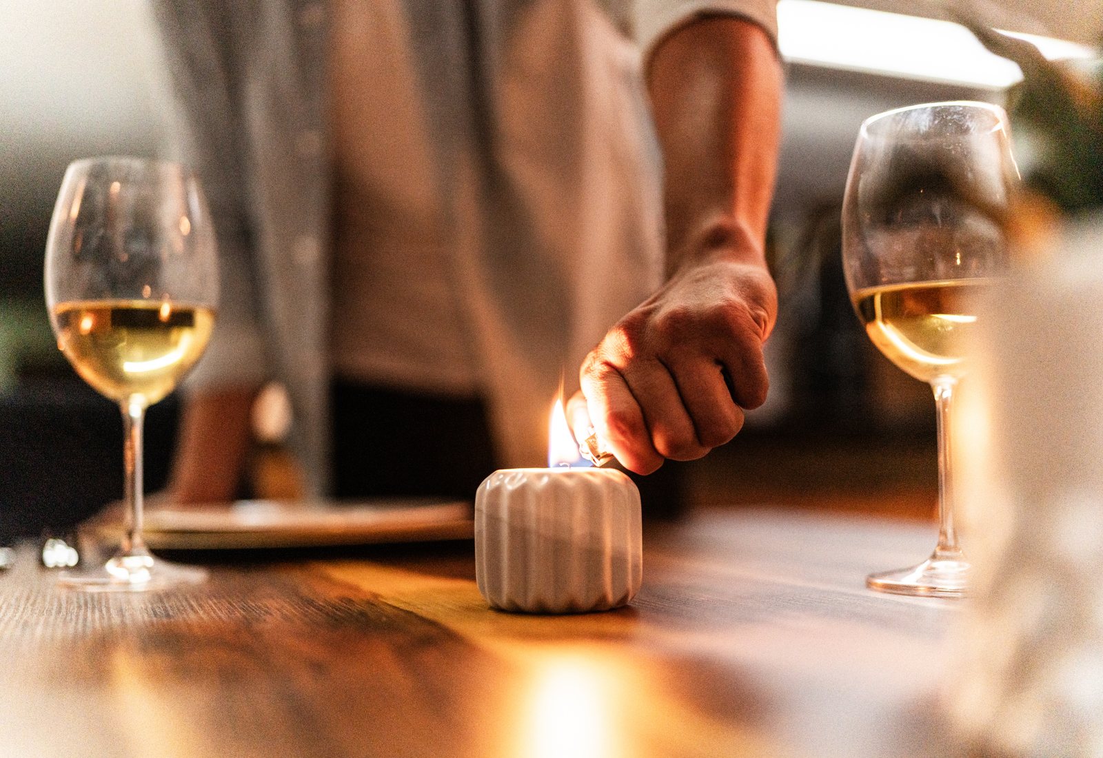 Two people holding hands across a softly lit dinner table